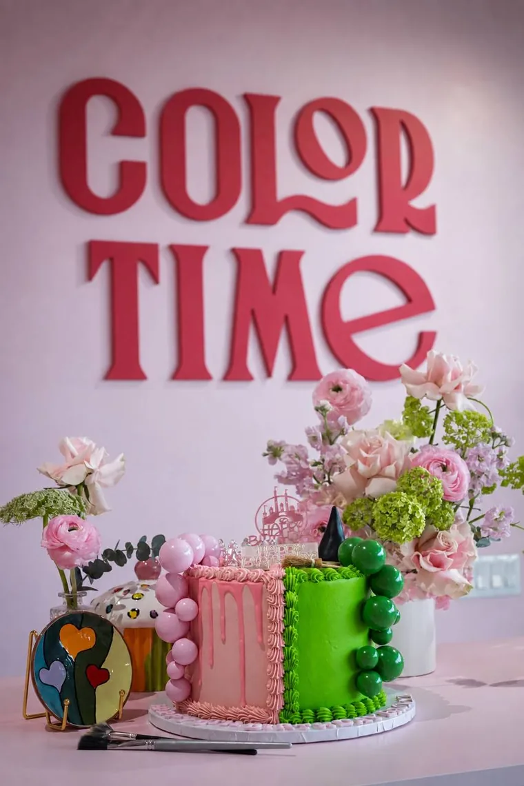 A pink and green birthday cake with flowers and painted ceramics at Color Time