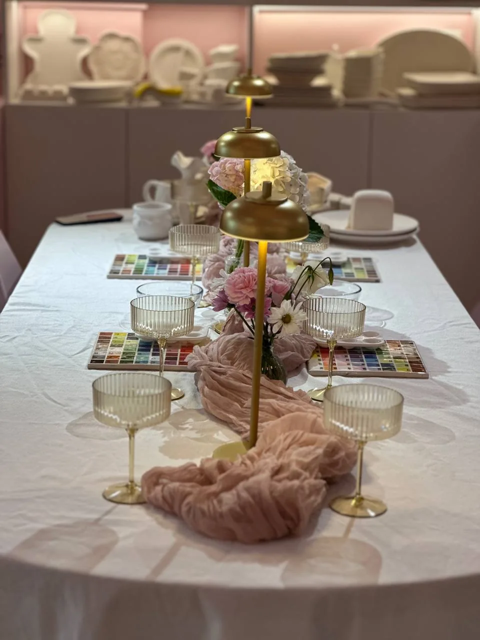 Decorated party table with flowers, gold lamps and coupe glasses